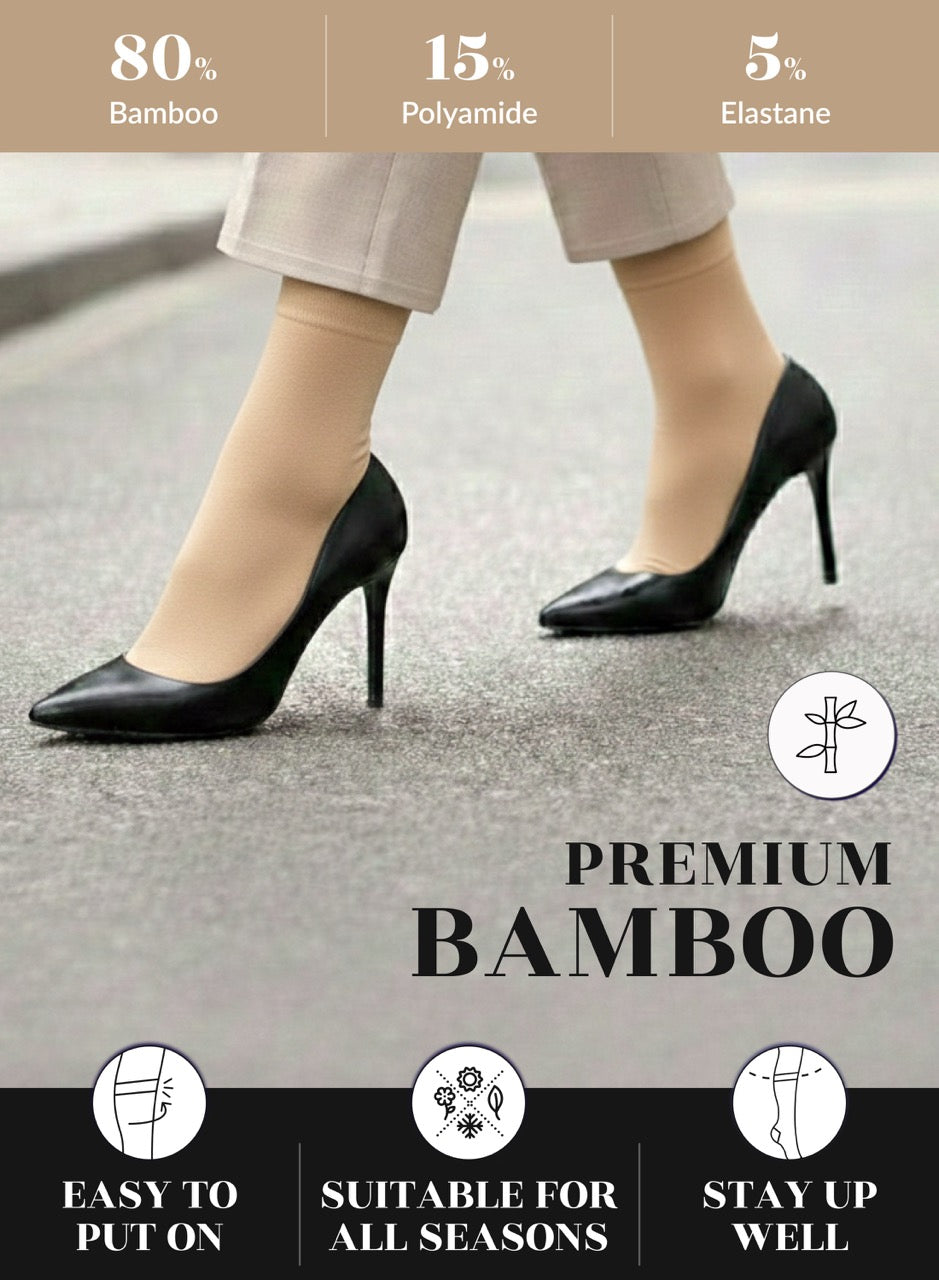 Person wearing black high heels with beige socks, showing shoe and part of leg on a neutral background.