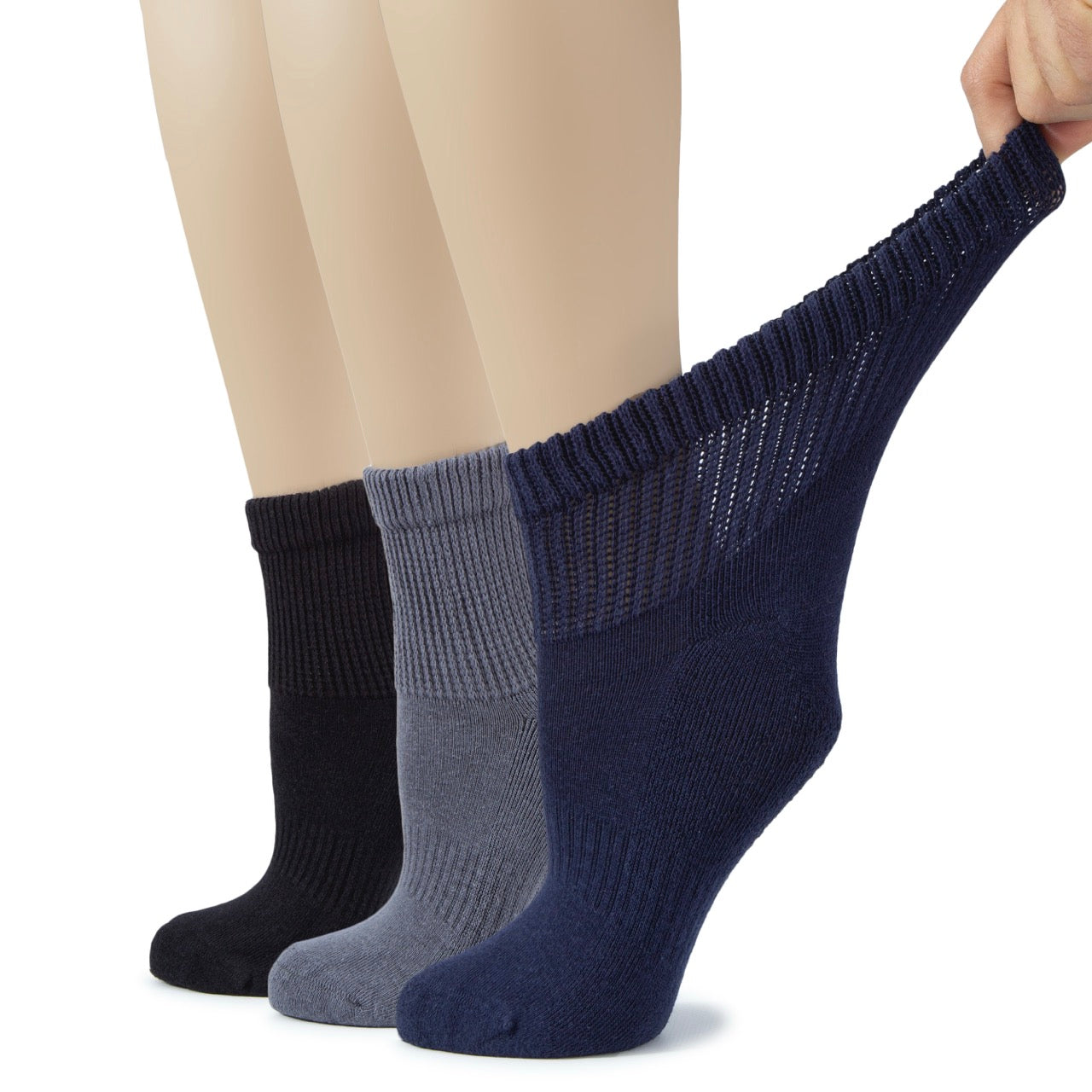 Three pairs of socks in black, medium gray, and navy blue being held above a person's legs.