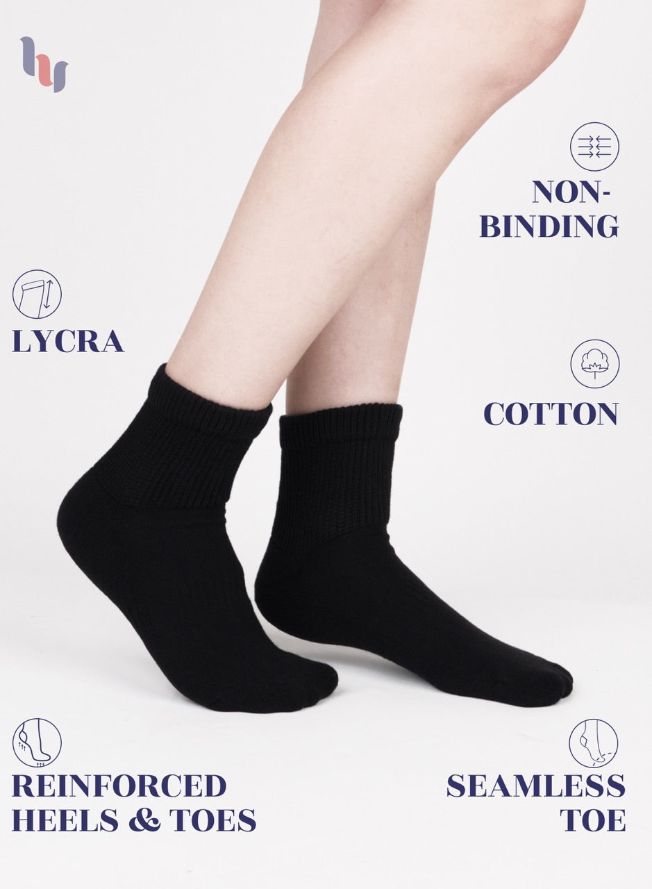 Black socks worn by a person on a white background with text highlighting features like LYCRA, non-binding, cotton, reinforced heels & toes, and seamless toe.