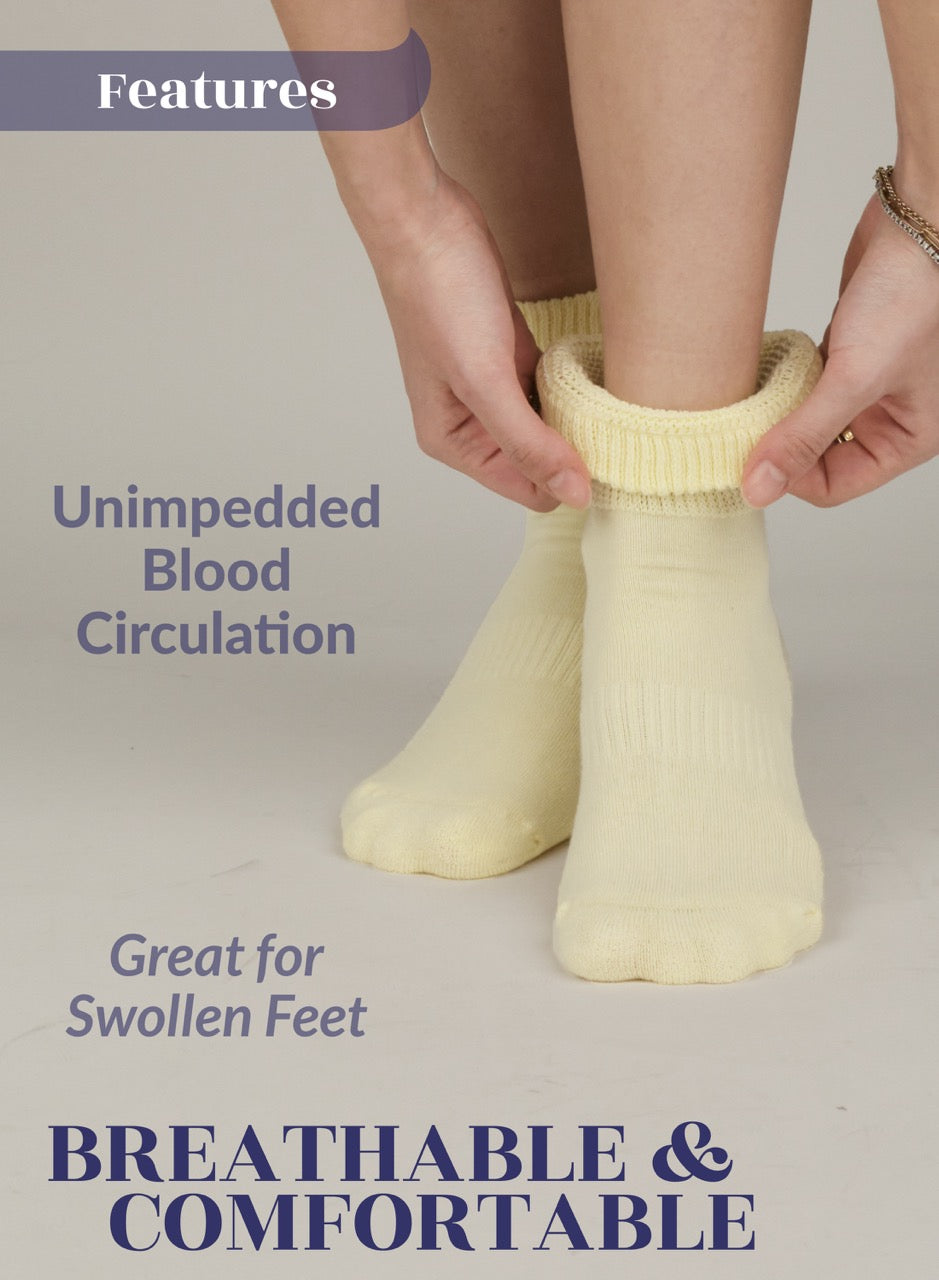 Person wearing a pair of Pastel Yellow diabetic socks with text highlighting features on a light gray background