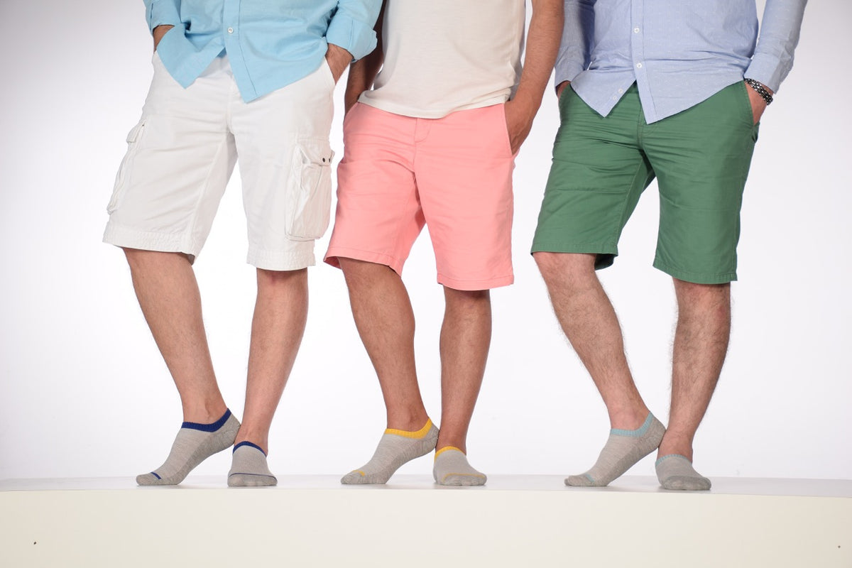 On a white surface, three men are seen wearing shorts and socks, with Cotton No-Show Socks for Men being the highlight.