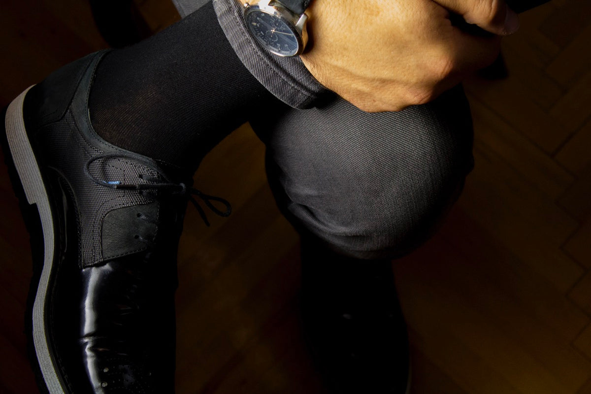 A gentleman donning black shoes and a watch, complemented by cotton crew socks.